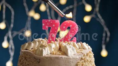 生日蛋糕，<strong>72</strong>个<strong>数字</strong>燃烧由较轻的粉红色蜡烛在蓝色的背面。 蜡烛被点燃了。 慢动作